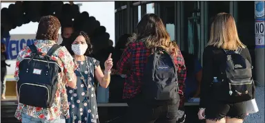  ?? (AP/The Yuma Sun/Randy Hoeft) ?? Virginia Legros, director of Guidance at Gila Ridge High School in Yuma, Ariz., explains the guidelines Thursday while greeting students arriving for the first day of on-campus instructio­n for students with last names M-through-Z.