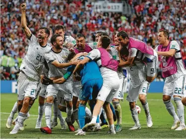  ?? Manu Fernandez / Associated Press ?? Russian players mob goalkeeper Igor Akinfeev, center, after the host nation defeated Spain at Luzhniki Stadium in Moscow on Sunday. Akinfeev stopped the final attempt in the shootout for the win.