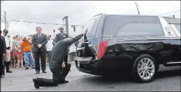  ?? GERALD HERBERT/THE ASSOCIATED PRESS ?? East Baton Rouge Sheriff Sid J. Gautreaux III kneels and places his hand on a hearse holding the casket of deputy Brad Garafola on Friday, at the scene where Garafola and two other Baton Rouge officers were killed and several others wounded.