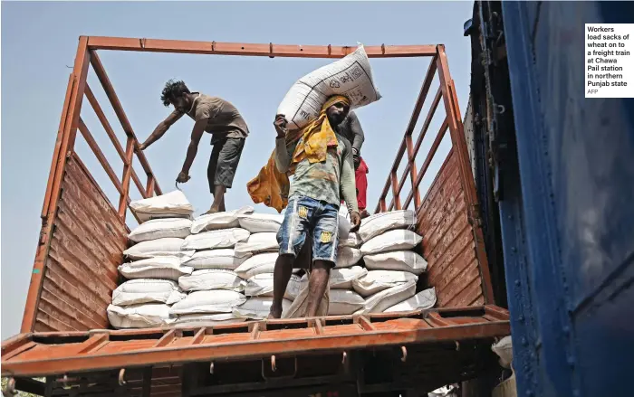  ?? AFP ?? Workers load sacks of wheat on to a freight train at Chawa Pail station in northern Punjab state