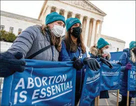  ?? PHOTOS BY ANDREW HARNIK/AP ?? Abortion rights advocates hold signs Wednesday that read “Abortion is Essential” as they demonstrat­e in front of the U.S. Supreme Court.