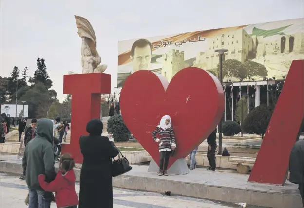  ?? PICTURE: HASSAN AMMAR/AP ?? A Syrian woman take a picture of her daughter in front of a banner showing Syrian president Bashar Assad at Saadallah al-jabiri Square in Aleppo