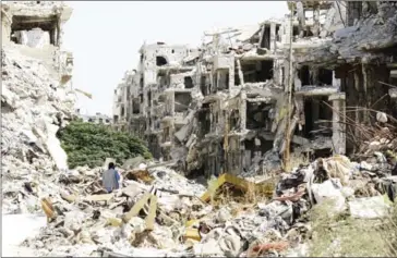  ?? LOUAI BESHARA/AFP ?? A man walks through destroyed buildings in the government-held Jouret al-Shiah neighbourh­ood of the central Syrian city of Homs on Monday.