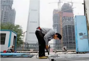  ??  ?? BEIJING: A worker assembles an aluminum platform outside a constructi­on site at the Central Business District of Beijing. China’s economic growth ticked higher to 6.9 percent in the first quarter of the year, according to the latest figures. —AP