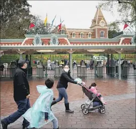  ?? Kent Nishimura Los Angeles Times ?? VISITORS walk toward the entrance of Disneyland in Anaheim on Friday, the last day that the theme parks were open through at least the end of the month.