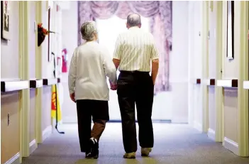  ?? MATT ROURKE/AP ?? An elderly couple walks down a hall in Easton, Pa. It’s not too late to get moving: Simple physical activity, mostly walking, helped high-risk seniors stay mobile after disability-inducing ailments even if, at 70 and beyond, they’d long been couch potatoes.