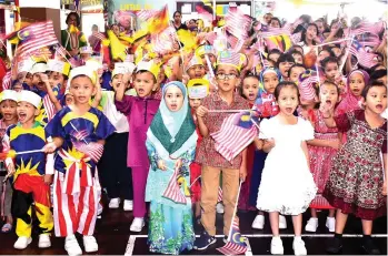  ??  ?? The children of SK St Rita and Tadika Muhibbah singing and waving the national flags during the celebratio­n