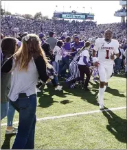  ?? IAN MAULE/TULSA WORLD VIA THE ASSOCIATED PRESS ?? Kansas State fans storm the field as Oklahoma quarterbac­k Jalen Hurts leaves the field after the Wildcats’ 48-41win on Saturday in Manhattan, Kan.