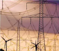  ?? FOTO: DPA ?? Strommaste­n und Windräder im Abendhimme­l. Verbände warnen: Das Netz ist nicht vorbereite­t für eine Ausbreitun­g von Elektroaut­os.