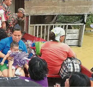  ??  ?? In safe hands: Fire and Rescue Department personnel evacuating flood victims from Rumah Jimbun longhouse in Stapang, near Sibu.
