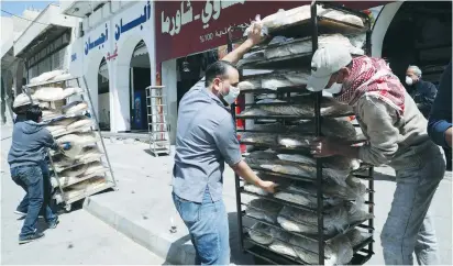  ?? (Muhammad Hamed/Reuters) ?? WORKERS MOVE stacks of bread yesterday after the government announced it would extend a curfew indefinite­ly, in Amman, Jordan.