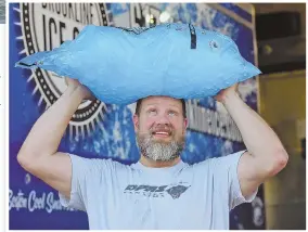  ??  ?? COOL JOB: Dan Deloge, above, an ice sculptor for Brookline Ice Co., was all smiles as he carried a bag of ice out of the warehouse to fill an order. Top, beachgoers beat the heat at Revere Beach.