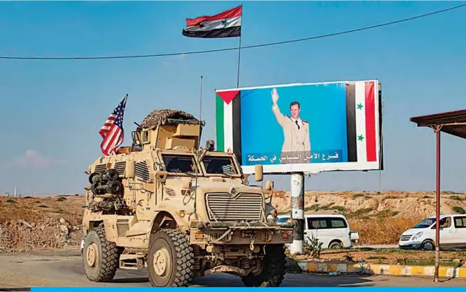  ??  ?? QAMISHLI: A US military vehicle drives near a checkpoint controlled by the Syrian government forces in Syria’s northeaste­rn city of Qamishli yesterday. —AFP