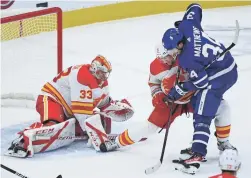  ?? AP ?? Maple Leafs center Auston Matthews (34) gets tied up by Flames defenseman Mark Giordano (5) as goaltender David Rittich (33) keeps a close eye on the loose puck during third period in Toronto on Monday.