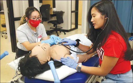  ?? PHOTOS BY STEVE MARCUS ?? Natalie Sanchez, left, a senior at Northwest Career & Technical Academy, and UNLV nursing student Yra Bognot listen for sounds from “Ann,” a medical mannequin, during Wednesday’s session of UNLV Nurse Camp for high school students. The five-day camp takes place at UNLV’S Kirk Kerkorian School of Medicine’s Clinical Simulation Center.