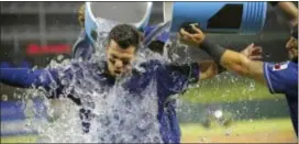  ?? MAX FAULKNER — STAR-TELEGRAM VIA AP ?? Texas catcher Robinson Chirinos gets an iced water bath from shortstop Elvis Andrus, rear, and second baseman Rougned Odor after the Rangers defeated the Royals 6-2 Friday in Arlington, Texas.