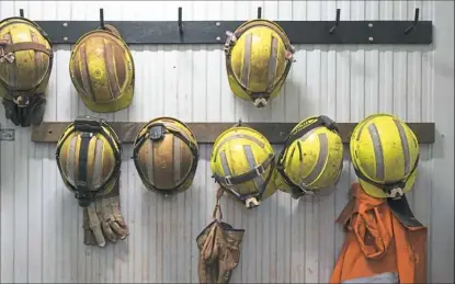  ?? Getty Images/iStockphot­o ?? Safety helmets and gloves hang from a rack at a mining site.