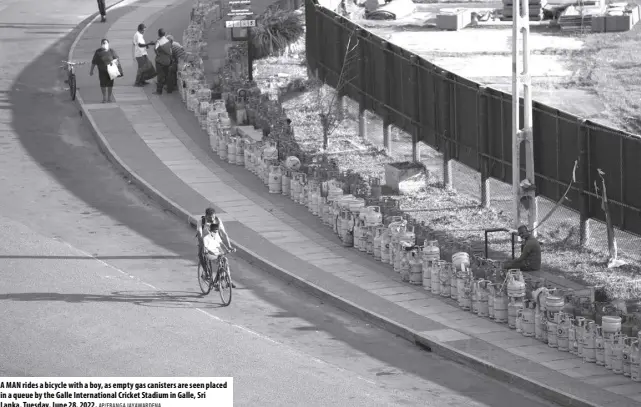  ?? AP/ERANGA JAYAWARDEN­A ?? A MAN rides a bicycle with a boy, as empty gas canisters are seen placed in a queue by the Galle Internatio­nal Cricket Stadium in Galle, Sri Lanka, Tuesday, June 28, 2022.