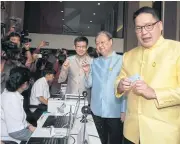  ?? SOMCHAI POOMLARD ?? Palang Pracharath Party leader Uttama Savanayana, right, leads key party figures to officially apply for their party membership­s on the first day of a recruitmen­t drive for members at the party’s office on Ratchadaph­isek Road in Bangkok yesterday.