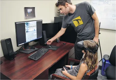  ?? UNIVERSITY OF GUELPH ?? Andrew Vierich, a software developer at the University of Guelph, looks on as student Ruby Corbett learns how to safely cross streets using a virtual reality program. Vierich helped design the program, which teaches kids to traverse a two-lane road in various scenarios.