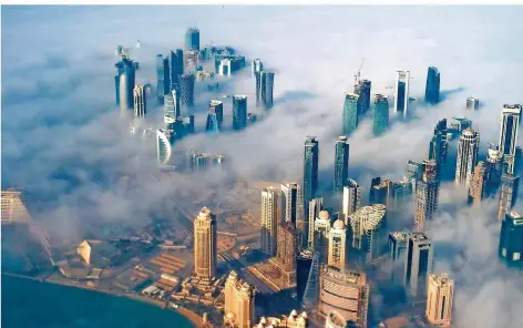  ?? FOTO: VALAT/DPA ?? Dichter Nebel verhüllt die Hochhäuser der Skyline von Doha – und die ins Zwielicht geratenen Geschäfte des Emirats noch weiter ins Dunkel.