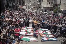  ?? KHALIL HAMRA/AP ?? Palestinia­ns attend the funeral of two women and eight children who were killed after an Israeli air strike Saturday in Gaza City.