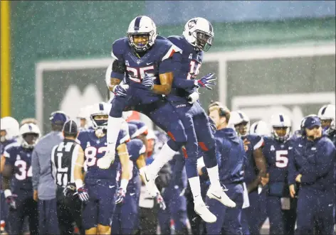  ?? Michael Dwyer / Associated Press ?? UConn defensive backs Tyler Coyle (25) and Tahj Herring-Wilson (14) celebrate after a stop against Boston College during the first quarter during a game at Fenway Park in Boston on Nov. 18.