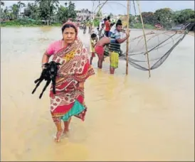  ?? PTI PHOTO ?? A woman walks to a safer place as many others catch fish at the flooded village of Srilanka Basti in Agartala on Tuesday.