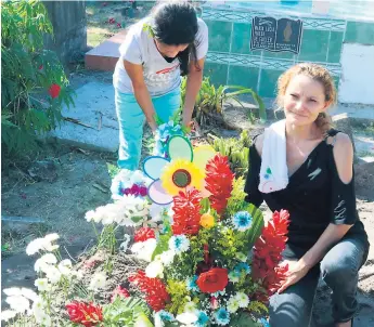  ??  ?? LUTO. Lourdes Guifarro coloca flores en la tumba de su hijo Cristhian Castillo, cuyos restos fueron enterrados ayer en el cementerio de la colonia Buenos Aires frente al Seguro Social.