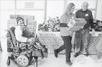  ?? SCOTT GARDNER THE HAMILTON SPECTATOR ?? Waleed Taher is all smiles as volunteers help him and his family shop at the Good Shepherd's Christmas Marketplac­e at the charity's Venture Centre on Cannon Street East Friday.