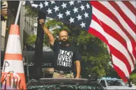  ??  ?? George Floyd’s name is written on the windshield as John Coy wears a shirt that reads Black Lives Matter and stands through his sunroof with his fist in the air at 16th Street Northwest renamed Black Lives Matter Plaza near the White House in Washington.
(AP/Andrew Harnik)