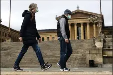  ?? MATT ROURKE - ASSOCIATED PRESS ?? A couple in protective masks during the coronaviru­s outbreak walk past the Philadelph­ia Museum of Art in Philadelph­ia, Friday, April 3, 2020. The museum has temporaril­y closed due to the COVID-19pandemic.