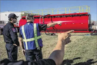  ?? TAMIR KALIFA / AMERICAN-STATESMAN ?? Fire officials show off the new tanker base, which sits beside an airstrip at Austin-Bergstrom Internatio­nal Airport. The base includes a huge cylindrica­l tank and a wheeled container that can be hitched to a truck and driven out to an air tanker.