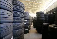  ?? Dreamstime/TNS ?? ■ Piles of new tires sit in a Tyre Warehouse car garage.