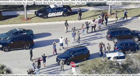  ?? AP ?? Students hold their hands in the air as they are evacuated by police from Marjory Stoneman Douglas High School in Parkland, Florida after a shooter opened fire on the campus in a photo taken on Feb. 14.