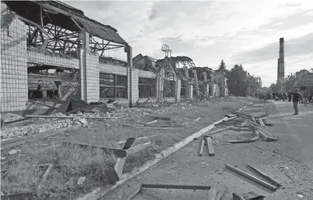  ?? NATACHA PISARENKO/AP ?? ABOVE: People view damage at a railway service facility near Kyiv, Ukraine, on Sunday. The railway buildings were hit by a Russian missile strike.