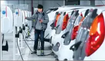  ?? XINHUA ?? A resident charges an electric car at an electric-car rental service bay in Shanghai.