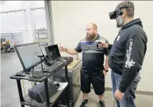  ?? DAVID ROSSITER/ THE CANADIAN PRESS ?? Instructor Chris DeLisle, left, works with student Mark Kokas on a simulator during a class at the Lethbridge College wind turbine technician program.