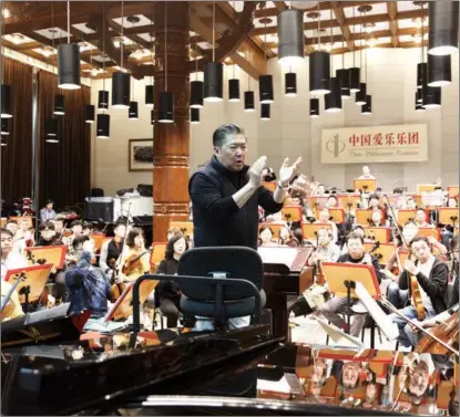  ?? JIANG DONG / CHINA DAILY ?? Conductor Yu Long (center) and musicians of the China Philharmon­ic Orchestra go through rehearsals early last year in Beijing. The orchestra staged a New Year concert on Dec 30.