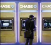  ??  ?? A customer uses an ATM at a branch of Chase Bank, in New York. Fewer Americans are without access to a checking or savings account, according to a survey released Thursday by federal regulators.
