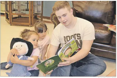  ?? ERIC MCCARTHY/JOURNAL PIONEER ?? Nick Handrahan, a member of the M.E. Callaghan Intermedia­te School charity committee, reads to Alia (left) and Laila Banks from one of the books the student committee provided for Kids West’s Family Resource Centre.