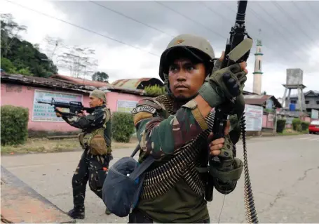  ??  ?? Government soldiers patrol a Marawi street behind the cover of a military vehicle in the early days of the Maute Group siege Reuters