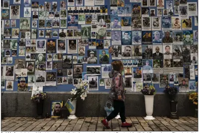  ?? (AP/Jae C. Hong) ?? A girl looks at photos of Ukrainian soldiers killed in the county’s war against Russia, at the Wall of Remembranc­e Thursday in Kyiv,
Ukraine.