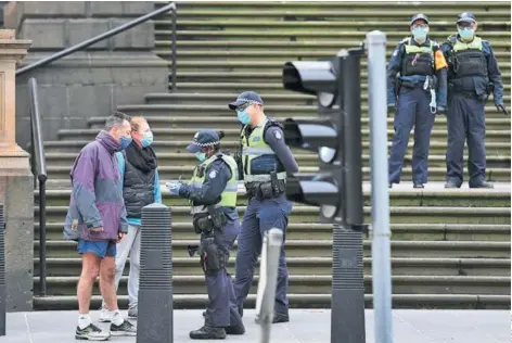  ??  ?? Policías verifican los datos de residentes en el distrito comercial central de Melbourne, en agosto.