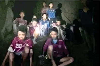  ??  ?? DESPERATE: The young footballer­s wait to be rescued deep inside the flooded Tham Luang caves in Thailand