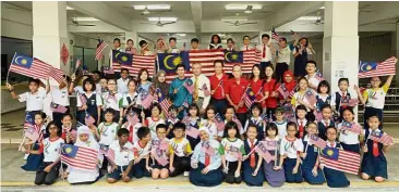  ??  ?? Starting young: SJKC Kheng Chee pupils raising their flags proudly along with the officials at the school canteen in Pusat Bandar Puchong.