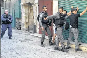  ?? AP PHOTO ?? Israeli border police officers body-search Palestinia­ns in Jerusalem’s Old City, Friday. Three Palestinia­n assailants opened fire on Israeli police from inside a major Jerusalem holy site Friday, killing two officers before being shot dead, police said.