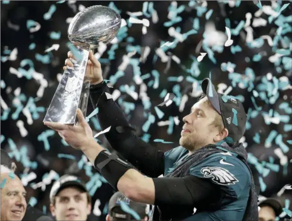 ?? CHRIS O’MEARA, MATT YORK - THE ASSOCIATED PRESS ?? Above, the Philadelph­ia Eagles’ Nick Foles holds up the Vince Lombardi Trophy after the NFL Super Bowl 52 football game against the New England Patriots, Sunday, F in Minneapoli­s. The Eagles won 41-33. Below right, the Eagles’ Zach Ertz dives into the...