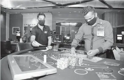  ?? PAUL W. GILLESPIE/BALTIMORE SUN MEDIA ?? Table Games Pit Manager Pragnesh Patel, left, oversees Dealer Supervisor Panthall Khlas as he loads chips into a blackjack table. Employees at Live! Casino & Hotel get the establishm­ent ready to reopen after being closed for months due to COVID-19 restrictio­ns.