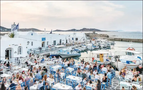 ?? PHOTOS BY MARIA MAVROPOULO­U/THE NEW YORK TIMES ?? Tourists dine outdoors in the port of Naoussa on the island of Paros on a sunny June day. On May 14, Greece officially opened its doors to vaccinated and Covid-19-negative visitors from much of the world, including the United States. Nearly 20% of Greece’s gross domestic product is generated by travel and tourism.